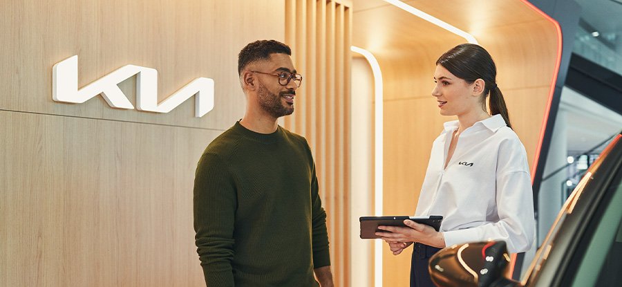 Ein Mann und eine Frau im Kia-Autohaus, die über ein Auto sprechen.